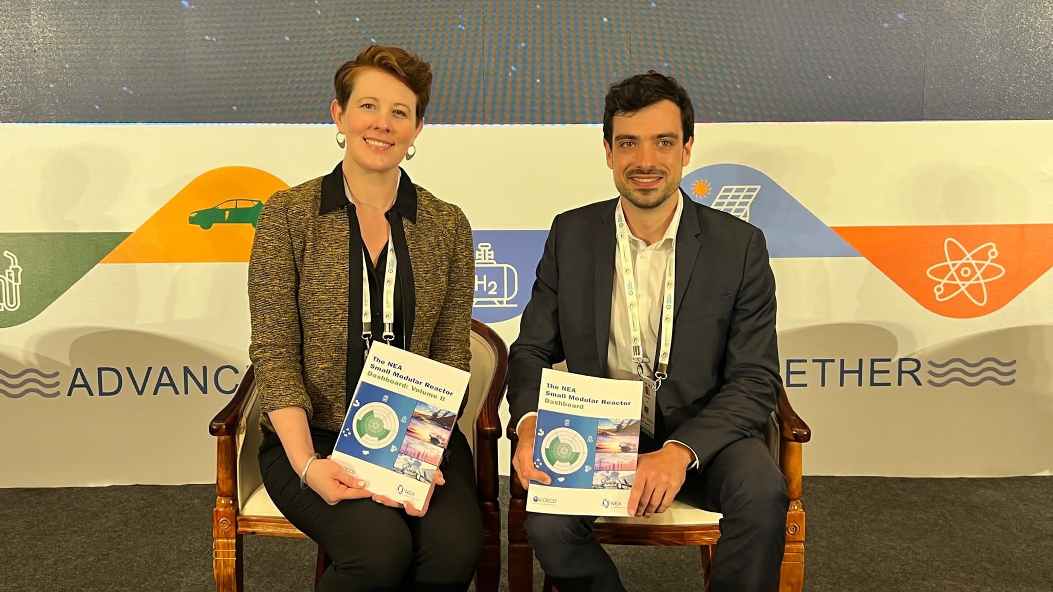 Lucas Mir and Dr Katy Huff hold a copy of the NEA SMR Dashboard: Volume II at CEM14.